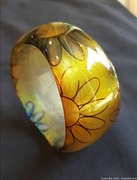 Side view of yellow lucite bangle showing floral design