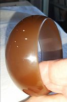 Side view of caramel Lucite bangle showing dome profile and surface sheen