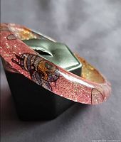 Side view of lucite bangle showing bee motif and glitter