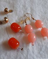 Both pairs of earrings on white cloth showing bead shapes and findings