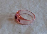 Side view of translucent pink lucite ring showing rhinestone settings