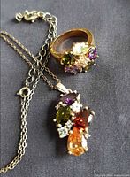 Pendant and ring showing multicoloured stones and silver-tone settings