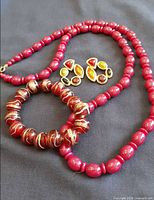Necklace, swirled glass bracelet and earrings on dark background