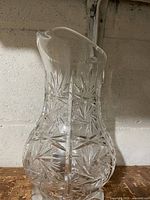 Full side view of clear cut glass pitcher showing starburst and paneled pattern