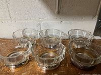 Six clear pressed glass bowls with silver-plated bases arranged on surface