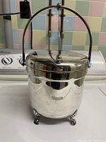 Full view of silver-plated ice bucket with handle raised