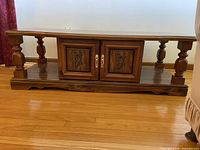 Front angled view showing entire coffee table with central cabinet, open shelves, turned columns, shaped base