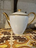 Full side view of teapot showing body, spout, handle, gold trim