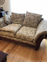 Full view of loveseat showing floral fabric upholstery and wooden frame