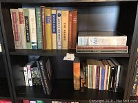 Books arranged on black shelving unit showing various classic and art books from multiple angles.