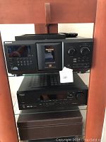 View of the Sony CDP-CX355 CD changer on shelf with additional audio equipment below.