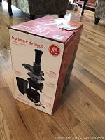 Front side view of the GE juice extractor box showing product image, brand logo and some product features in Spanish.