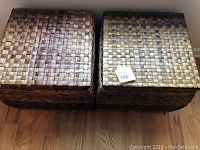 Two woven wicker baskets with lids closed, set on wooden floor