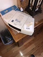 Photo of a white Bose Wave Music System on a wooden table, showing numeric keypad, display screen, and control buttons with some surface dirt and marks.