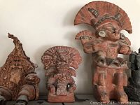 Close-up of three terracotta-style tribal figures and a gnome-like figure.