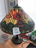 Full view of the stained glass table lamp showing the floral patterned lampshade and dark base.