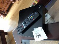 Sony Blu-ray player and remote control placed on a wooden surface, showing overall good condition.