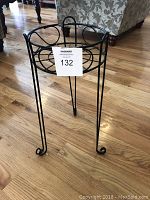 Front angle view of the black metal plant stand on hardwood floor.