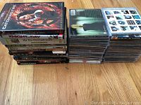 Stack of assorted DVDs and CDs showing movie titles and standard CD cases.