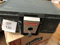 Black Honeywell safe with key inserted in the lock on front.