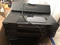 Front view of the Sony CDP-CX100 100 disc changer showing buttons, jog dial, display and disc loading mechanism.