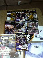 Assorted Ravens’ Report programs, fan guide and outreach book spread on table