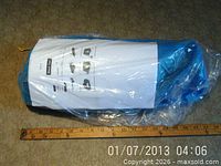 Rolled blue tent in plastic beside ruler