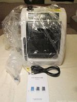 main unit wrapped in plastic, power cord and manual visible