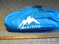 Blue Maizoa carry bag holding tent, ruler showing size