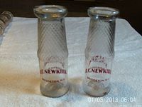 Two matching R.C. Newkirk glass milk bottles standing on towel