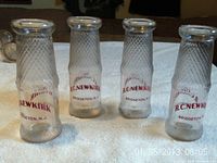 Four clear glass milk bottles standing upright, front view