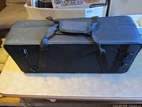 Top view of closed black trumpet case showing carry handle and shoulder strap