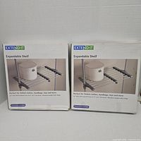 Front view of two boxed Extend-It expandable shelves