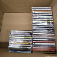 Stacked sealed audio CDs in box showing spines