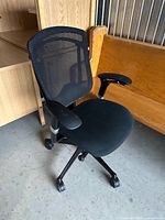Full view of black mesh office chair showing seat, backrest, base and casters