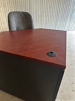 Corner desk top, reddish-brown laminate with chair behind