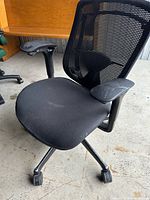 Front-left view of black mesh back office chair on casters