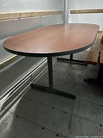 Full view of conference table side profile showing oval top and T-leg base