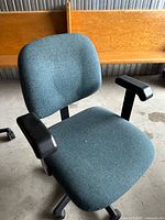 Front angled view of the green fabric office chair showing seat, backrest, armrests, and base
