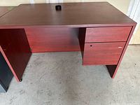 Front view of cherry-finish desk showing worksurface, right-side drawers, grommet