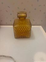 Front view of square amber glass decanter with stopper