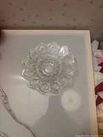 Top view of clear pressed glass charger showing full floral starburst design