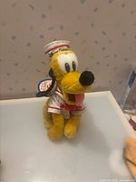 Full view of Pluto plush seated on surface