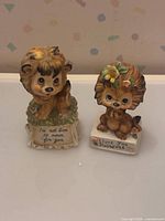 Front view of both ceramic lion cub figurines showing inscriptions and floral accents