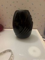 Front view of black glossy ceramic vase showing swirl ribbed pattern