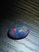Oblique view showing multicolor flashes on black opal cabochon