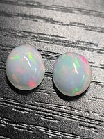 Both opal cabochons showing play-of-colour on textured background