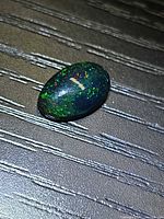 Top view of oval Ethiopian black opal showing green and red pinfire play-of-color