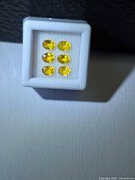 Front view of six oval yellow sapphires in white display box