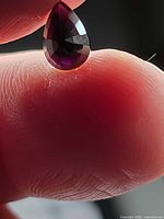 Pear-cut purple spinel held between fingers